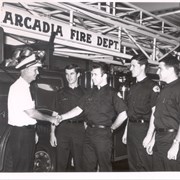 Pictured in front of snorkel fire truck is Assistant Fire Chief Bruce Moore, congratulating new firemen.  L-R they are: Lee Craven, Bob Madden, Don Cross, and George Truppelli.
