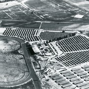 Aerial view taken looking southeast from position about over present Arboretum.  Photo shows Santa Anita Park, probably in opening season.  Present City Hall sits in area just beyond cars parked at east end of track.  Part of oval of old Santa Anita track built by Elias J. "Lucky" Baldwin is seen in upper portion of photo, in area that is now Arcadia County Park.  Duarte Road is seen crossing photo in upper right corner.  Present Arcadia County Park area is in this photo, bordered on the north by Pacific Electric Railroad tracks.  A train has just brought a group to the races and they are seen walking in center of photo.  White square seen near right side, is slab left from hangars when U.S. Army Balloon School occupied this site, 1917-1927.